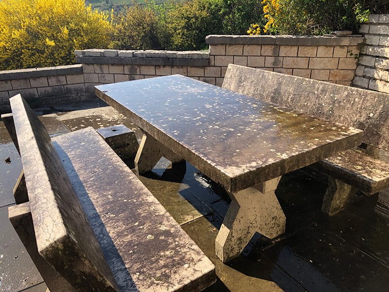 Tavolo e pavimento in pietra da pulire da muschi e licheni